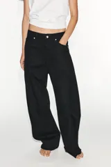 Jeans de tiro medio estilo balloon en color negro, con diseño de cinco bolsillos, trabillas para cinturón y cierre frontal con cremallera y botón metálico.