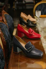 Zapato de cuero rojo con aplique decorativo en el empeine y tacón cuadrado.