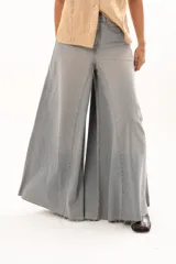 Pantalón de jean tiro alto con diseño de pierna extra ancha y caída fluida. Presenta costuras verticales que realzan su estructura, bolsillos funcionales y terminación de ruedo deshilachado.