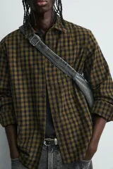 Bolso tipo bandolera confeccionado en tejido denim de algodón con efecto lavado. Cuenta con un compartimento principal con cierre de cremallera, un bolsillo interior con cierre y dos bolsillos frontales, uno con cierre de cremallera y otro con cierre de fruncido. Incluye asa de hombro ajustable.