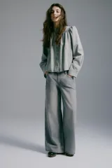 Jean de corte wide leg y tiro medio en denim color gris deslavado, con diseño de cinco bolsillos y cierre frontal con botón y cremallera.