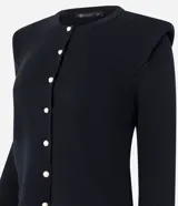 Cardigan de punto color blanco, de corte regular y ajuste al cuerpo. Presenta cuello redondo, mangas largas, cierre frontal con botones delicados y hombreras estructuradas que aportan volumen a la silueta.