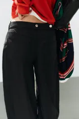 Jeans negro de tiro medio con corte balloon fit, diseño de cinco bolsillos y bajo acabado en puño con abertura y botón.