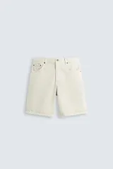 Bermuda de denim de algodón color beige claro, de corte regular fit y largo hasta la rodilla. Presenta cinco bolsillos y cierre frontal con cremallera y botón.