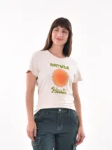 Remera de manga corta color crema con cuello redondo. Presenta un estampado frontal con un sol estilizado en tonos naranja y amarillo, y texto en verde que dice "NATURE Heals".