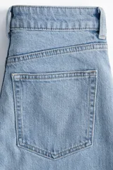 Pantalón de jean celeste de tiro alto, corte ancho y recto, con cinco bolsillos y cierre con botón.