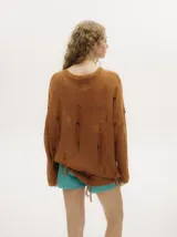 Sweater de punto semiabierto color naranja, con diseño holgado tipo vestido, detalles rasgados, flecos y canutillos de madera. Presenta bordados en crochet en cuello y puños, con pespuntes en hilo grueso en la sisa.