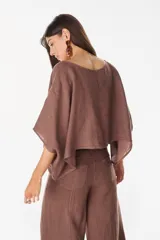 Blusa de lino italiano color blanco, con diseño holgado, escote asimétrico estilo off-shoulder y mangas cortas amplias.