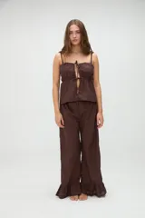 Top de pijama blanco confeccionado en algodón, con tirantes finos, escote recto y aberturas frontales con lazos ajustables.