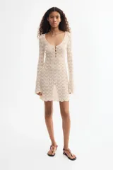 Vestido mini de punto de viscosa estilo crochet, con escote en V y botones frontales. Cuenta con mangas largas y ribetes festoneados en los puños y el bajo.