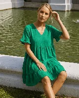 Vestido corto de lino verde, con escote en V, mangas cortas con volados y diseño escalonado en la falda.