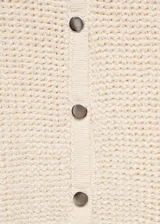 Cardigan de punto de manga corta con diseño crop y cuello redondo. Presenta cierre frontal con botones y una textura de tejido en relieve.