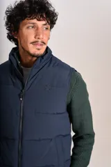 Chaleco puffer de color azul marino, con cierre frontal completo y cuello alto. Presenta un diseño acolchado horizontal y el logo de la marca bordado en el pecho.