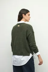 Sweater de tejido tramado en color verde oliva, con cuello redondo y mangas largas. Presenta un diseño de textura acanalada vertical.