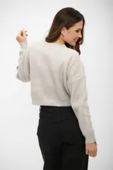 Buzo de tejido de punto con acabado brillante, cuello redondo, mangas largas y corte cropped.