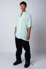 Camisa de manga corta con cuello cubano, confeccionada en fibrana premium. Presenta un corte oversize y cierre frontal con botones al tono.