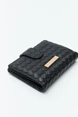 Billetera de mujer Daniel Cassin con diseño trenzado, cierre con broche a presión y placa metálica dorada con el logo de la marca en el frente.