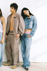 Cazadora crop de denim celeste desgastado, con cuello solapa, manga larga y bajo deshilachado. Presenta parches en forma de corazón en los bolsillos delanteros y detalles de roturas.