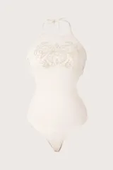Malla enteriza color beige con cuello halter alto, tirantes para anudar al cuello, detalle de bordado con cuentas en el pecho y fruncidos en los laterales.