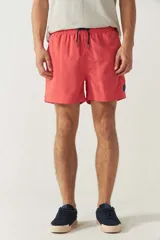 Short de baño liso color coral con cintura elástica, cordón ajustable, dos bolsillos laterales y uno trasero.