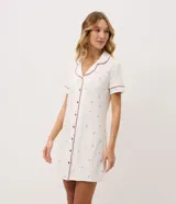 Camisón corto color blanco marfil con estampa floral sutil, cuello solapa, mangas cortas y cierre frontal con botones. Cuenta con ribetes en contraste en cuello y puños.