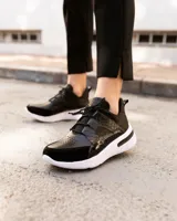 Championes deportivos de cuero en tonos marrón, tostado y marrón oscuro, con detalles de estampado animal print de leopardo en el lateral, suela gruesa blanca y cordones elásticos.