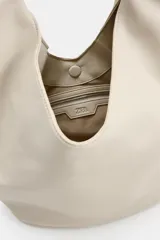 Bolso de hombro de gran tamaño color beige, con diseño hobo de líneas suaves, asa ancha integrada y cierre superior con imán.