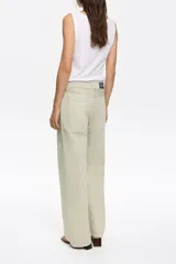 Pantalón vaquero de corte wide leg en color verde claro. Presenta un diseño de tiro medio con cierre frontal de botón y cremallera, además de cinco bolsillos clásicos.
