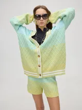 Cardigan de punto con diseño degradé en tonos tierra, patrón de rombos en relieve, cuello en V con cartera de botones y puños con rayas blancas y marrones.