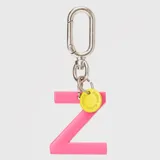 Llavero con dije en forma de letra A color rosado y pequeño dije circular amarillo con logo de la marca grabado. Incluye gancho metálico tipo mosquetón.