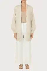 Saco abierto de punto en color beige, con diseño de manga larga y puños acanalados. Presenta un tejido con sutiles destellos brillantes integrados.