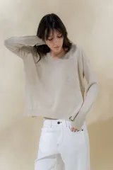 Sweater color beige de tejido de punto con brillo, escote en V y mangas largas.