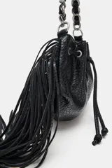 Bolso tipo saca color negro, de formato mini, con flecos laterales, cierre fruncido con cordones y correa combinada de cadena y tira de cuero sintético.