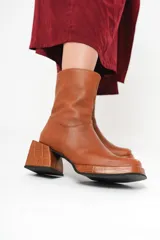 Bota de cuero color marrón con caña media, plataforma delantera de 2 cm y taco cuadrado de 7 cm.