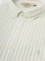 Camisa de hombre de manga larga con rayas verticales en tonos verde claro y blanco. Confeccionada en una mezcla de lino y algodón, presenta cuello abotonado y bolsillo en el pecho.