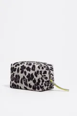 Neceser de tamaño mediano con estructura blanda, exterior de nylon con estampado de leopardo en tonos grises y negros, y cierre de cremallera. Presenta un tirador de cremallera con detalle de cordón trenzado en amarillo neón.