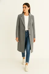 Tapado de corte recto y largo midi, confeccionado en tejido texturizado color gris. Presenta solapas clásicas, cierre frontal con botones y mangas largas.