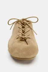 Zapato tipo blucher de estilo deportivo confeccionado en piel, con cierre mediante cordones, tirador trasero y detalle de pespuntes en el cuerpo. Presenta punta redonda y suela plana.