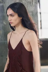 Vestido midi de viscosa color borgoña, con escote en V, tirantes finos ajustables, bordados a tono y volantes en el mismo tejido. El bajo es asimétrico.