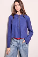 Sweater azul de tejido de punto acanalado, con cuello alto, cierre metálico frontal parcial y mangas largas.