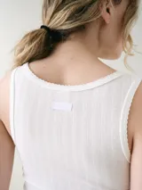 Musculosa básica entallada de tela pointelle color blanco, con escote redondo y detalle de ondas en los bordes.