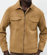 Campera estilo Harrington con diseño trucker, confeccionada en gamuza sintética color tostado. Presenta cuello clásico, cierre frontal por cremallera, bolsillos delanteros con solapa y mangas largas.