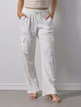Pantalón cargo de lino a rayas verticales grises y blancas, marca Marissa Olivia. Pretina ancha elastizada con lazo de ajuste, bolsillos inclinados delanteros y bolsillos laterales con botón.