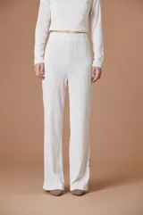 Pantalón de corte recto y silueta amplia, confeccionado en tejido con textura plisada de líneas verticales onduladas. Presenta cintura elástica y una caída fluida.