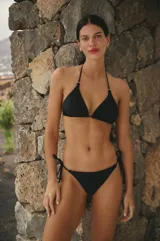 Conjunto de bikini negro de lycra mate, con corpiño triangular y bombacha vedetina con tiras laterales regulables.