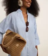 Salida de playa tipo camisa confeccionada en voile de algodón BCI con estampado de rayas verticales, cuello camisero, mangas largas y abotonado delantero.