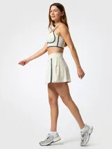 Skort deportivo color beige con detalles de líneas azul marino en los laterales y short interior integrado.