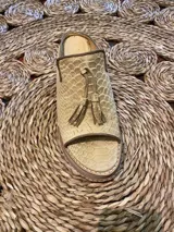 Sandalia de cuero color beige con textura de piel de serpiente, con puntera abierta y detalle de flecos.