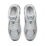 Championes urbanos New Balance modelo 2010, color gris con detalles en blanco y negro. Confeccionados con una combinación de malla transpirable, nobuk y materiales sintéticos. Presentan entresuela con tecnología ABZORB para absorción de impactos, inserciones SBS en talón y antepié, y refuerzo TPU Stability Web en la zona media.