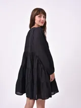 Vestido corto negro con escote redondo, mangas largas abullonadas y falda de tres volados.